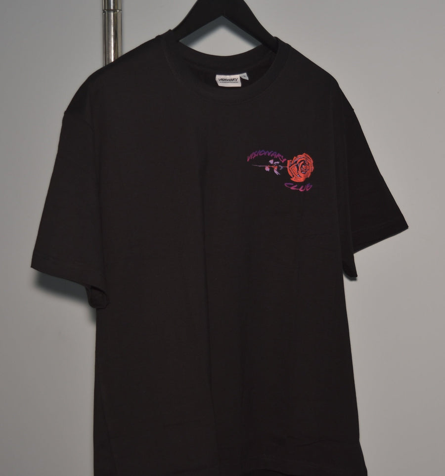Black t-shirt with a small logo on a hanger against a gray background