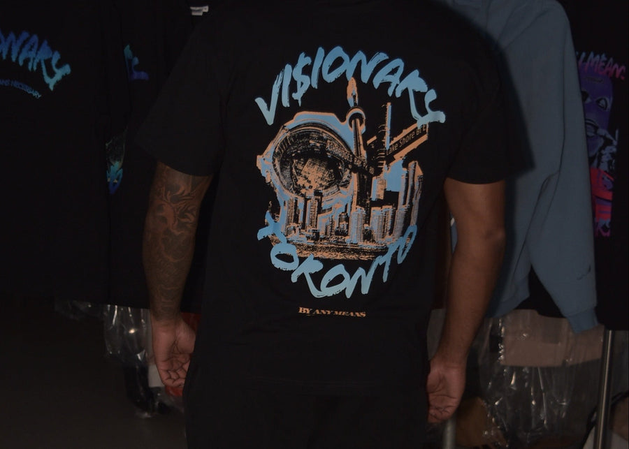 Person wearing a black t-shirt with 'Visionary Toronto' design in a clothing store.